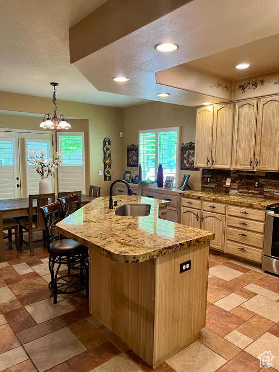 Kitchen featuring light brown cabinets, range, healthy amount of natural light, backsplash, and a textured ceiling