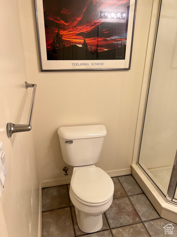 Full bathroom featuring baseboards, a stall shower, toilet, and tile patterned flooring