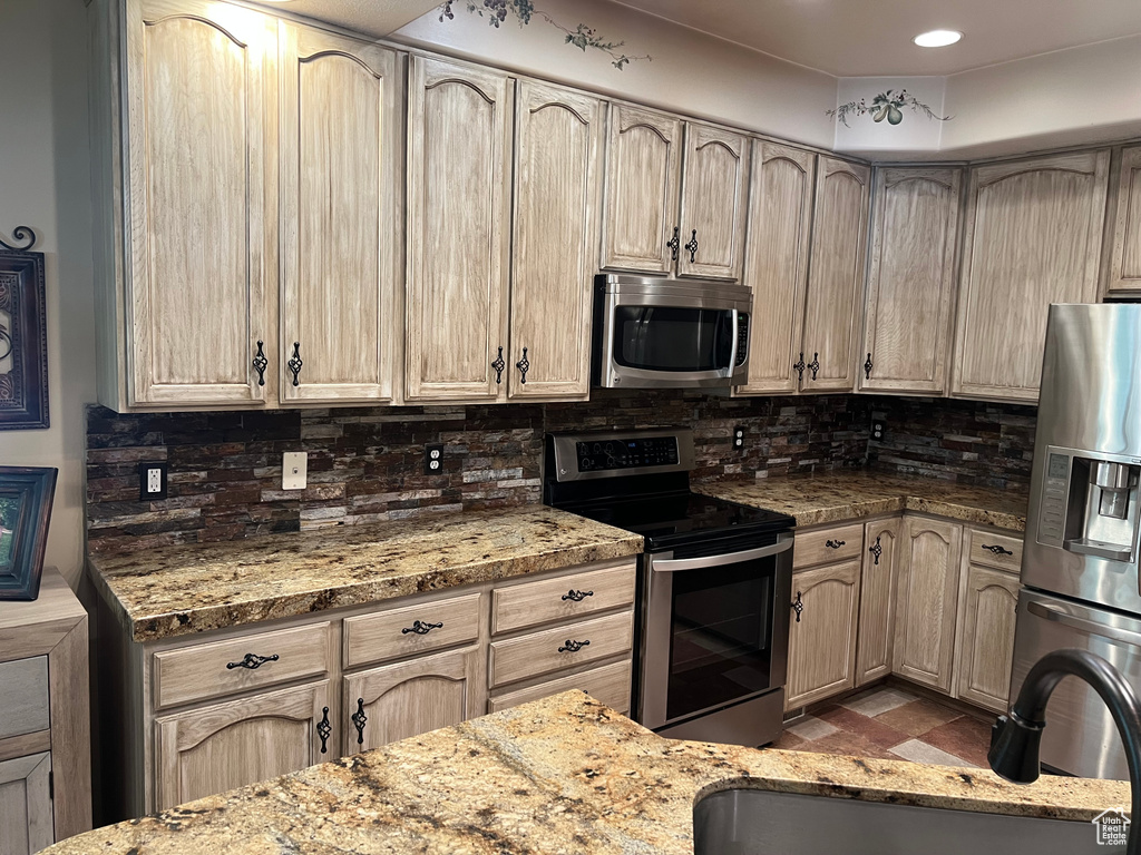 Kitchen featuring appliances with stainless steel finishes, tasteful backsplash, and light stone countertops