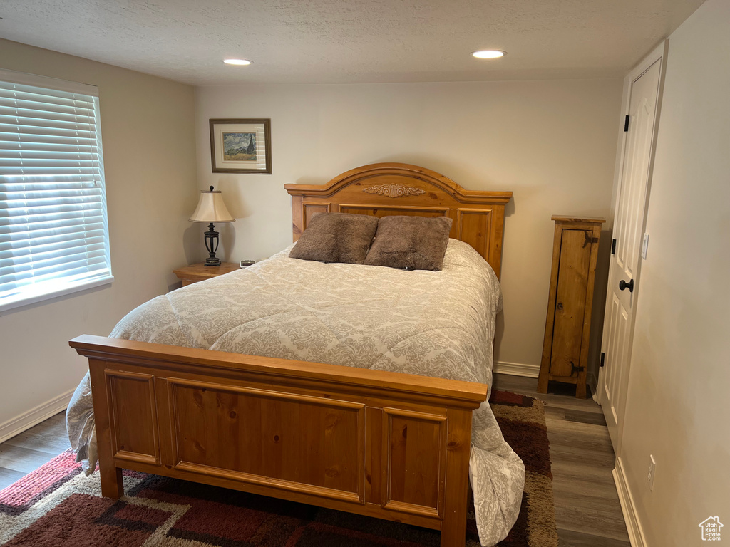 Bedroom featuring dark wood finished floors, multiple windows, baseboards, recessed lighting, and a textured ceiling