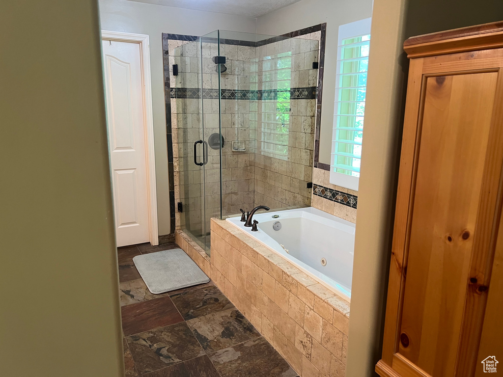 Full bath with a whirlpool tub, a stall shower, and stone tile floors