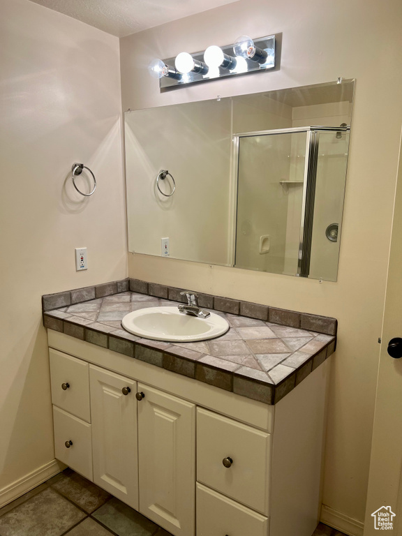 Bathroom with vanity, a shower stall, and tile patterned flooring