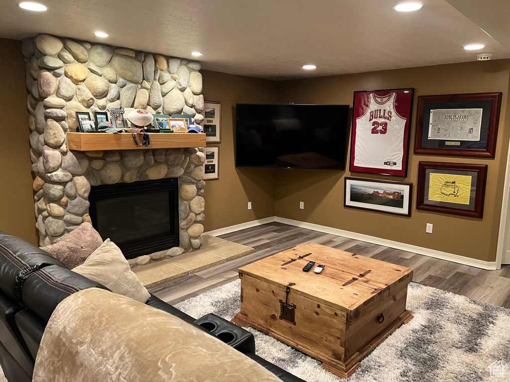 Living room featuring a fireplace, baseboards, wood finished floors, and recessed lighting