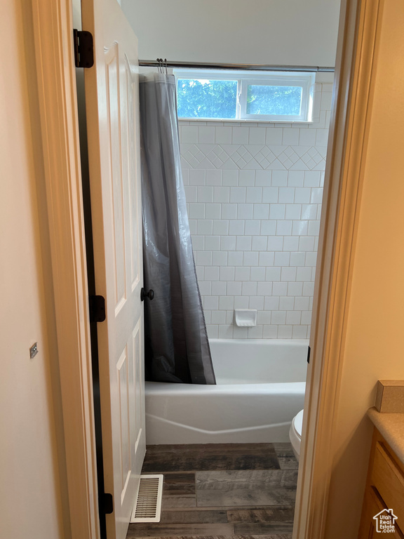 Full bathroom with vanity, shower / bath combo with shower curtain, wood finished floors, and toilet