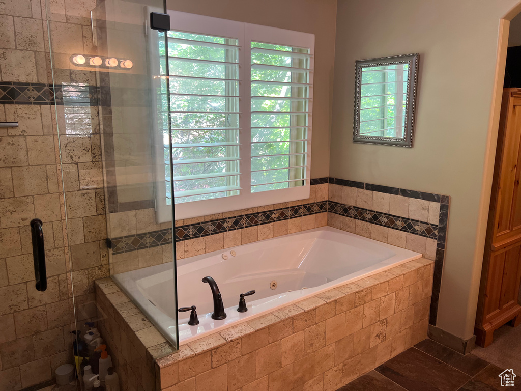 Bathroom with plenty of natural light, a jetted tub, and a stall shower