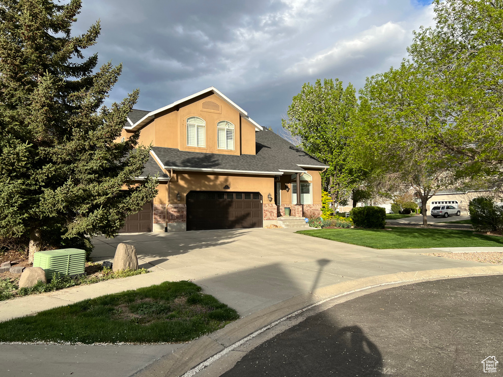 View of front of property with an attached garage, stucco siding, driveway, and a shingled roof