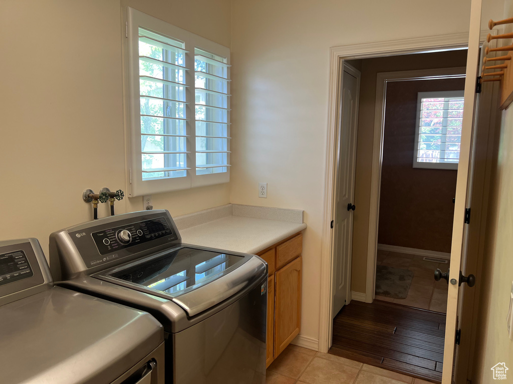 Laundry room with washer and clothes dryer, cabinet space, and light tile patterned flooring