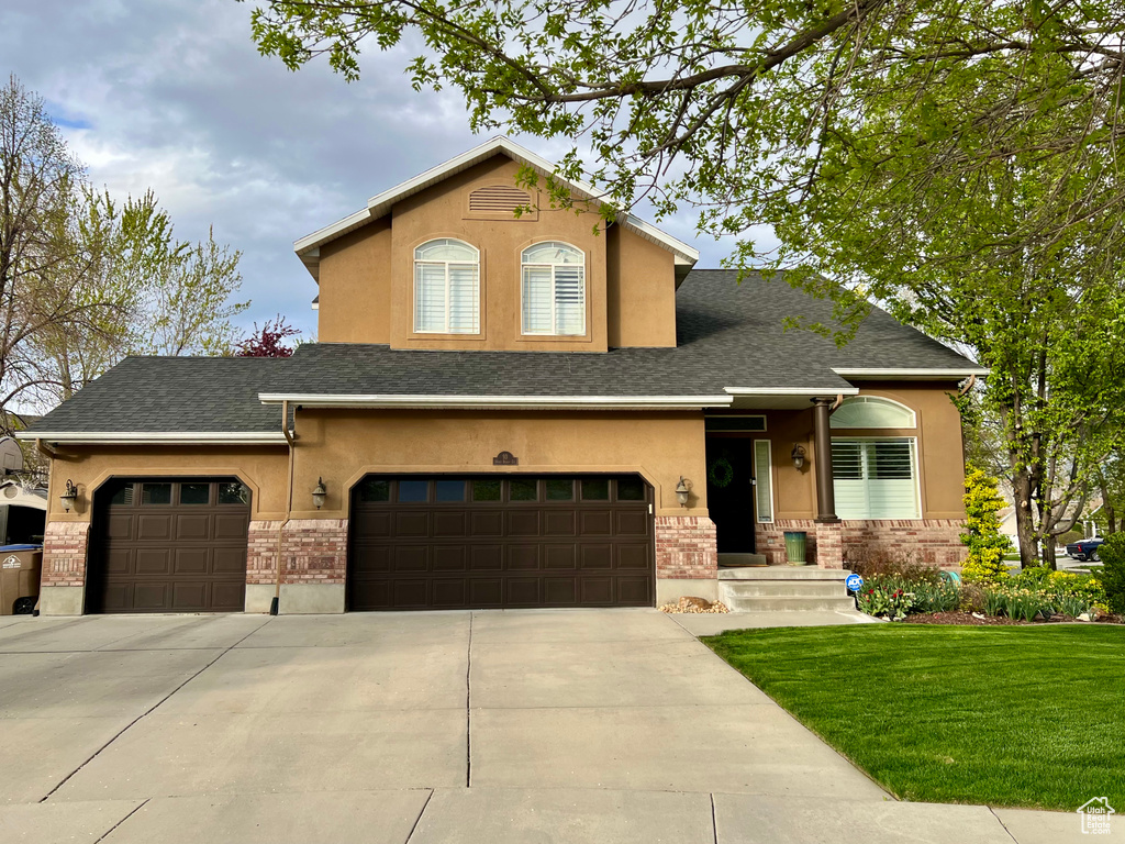Traditional-style house featuring stucco siding, driveway, and a front yard