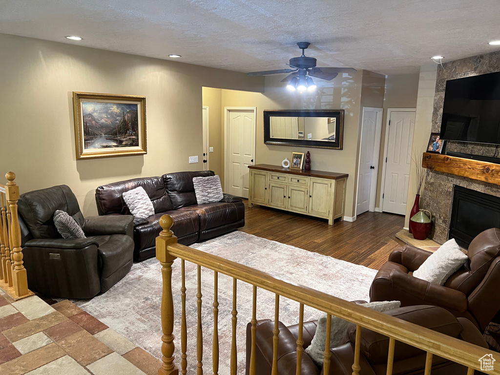 Living room with a fireplace, a ceiling fan, wood finished floors, and recessed lighting