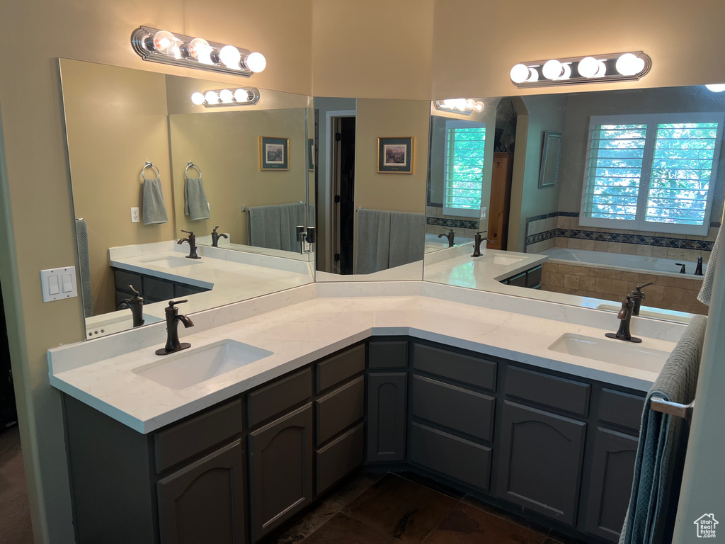 Bathroom featuring a garden tub, double vanity, and tile patterned flooring