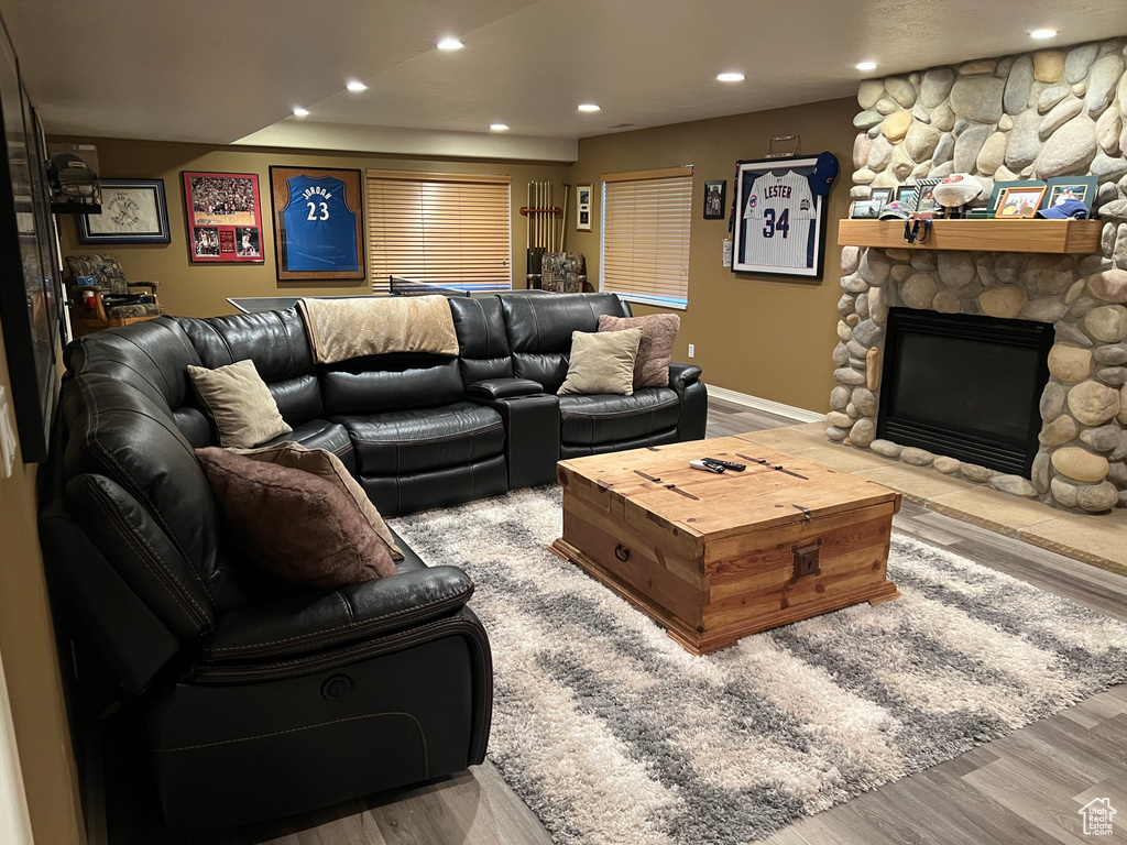 Living area with wood finished floors, recessed lighting, a stone fireplace, and baseboards