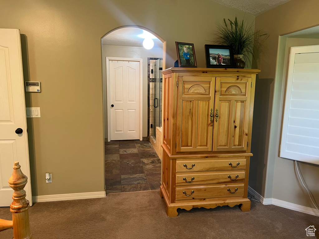 Bedroom with arched walkways, dark carpet, and baseboards