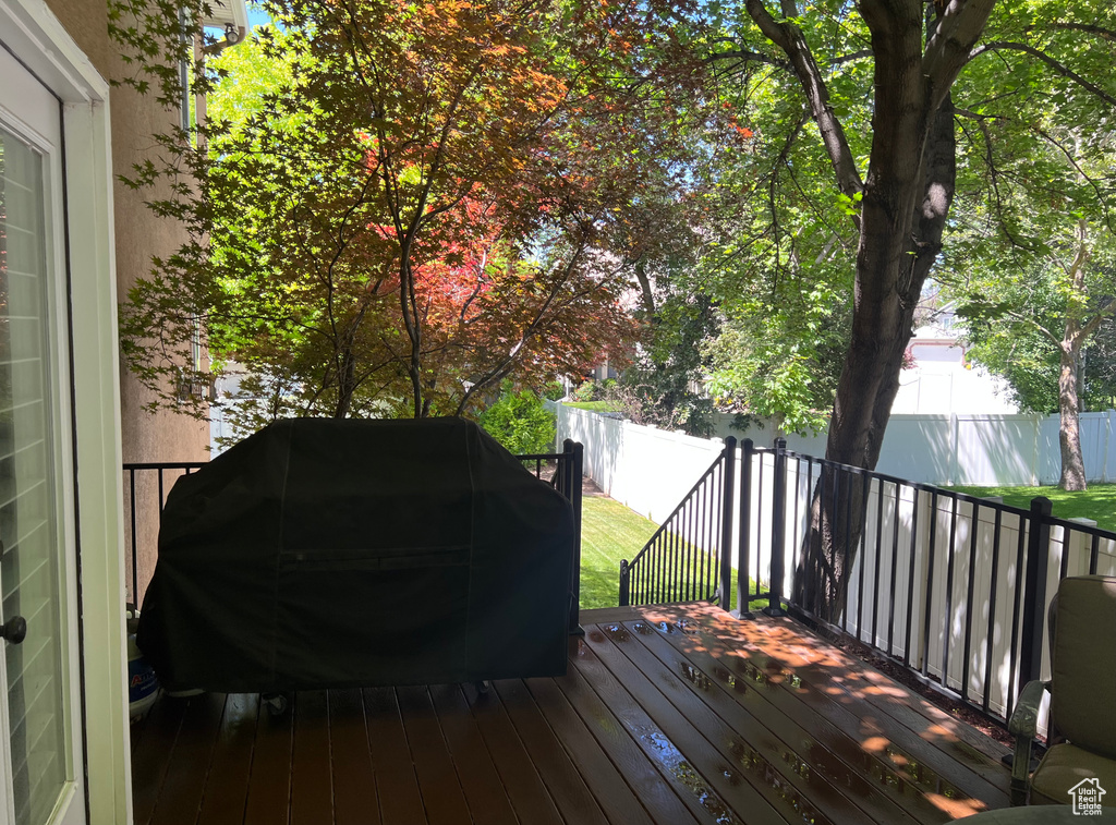 Wooden terrace with grilling area and a fenced backyard