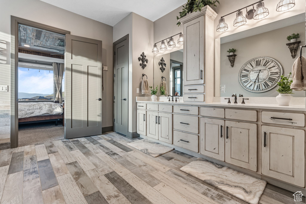 Full bath featuring wood finished floors, double vanity, connected bathroom, and healthy amount of natural light