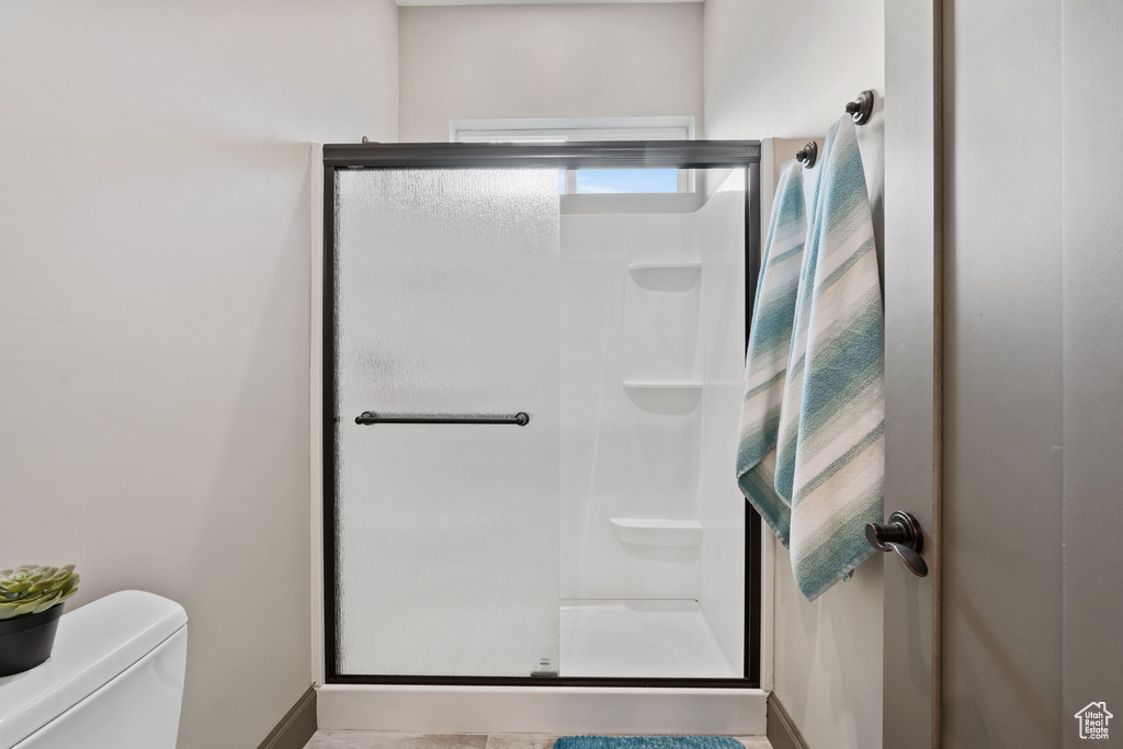 Bathroom with a shower stall, baseboards, and toilet