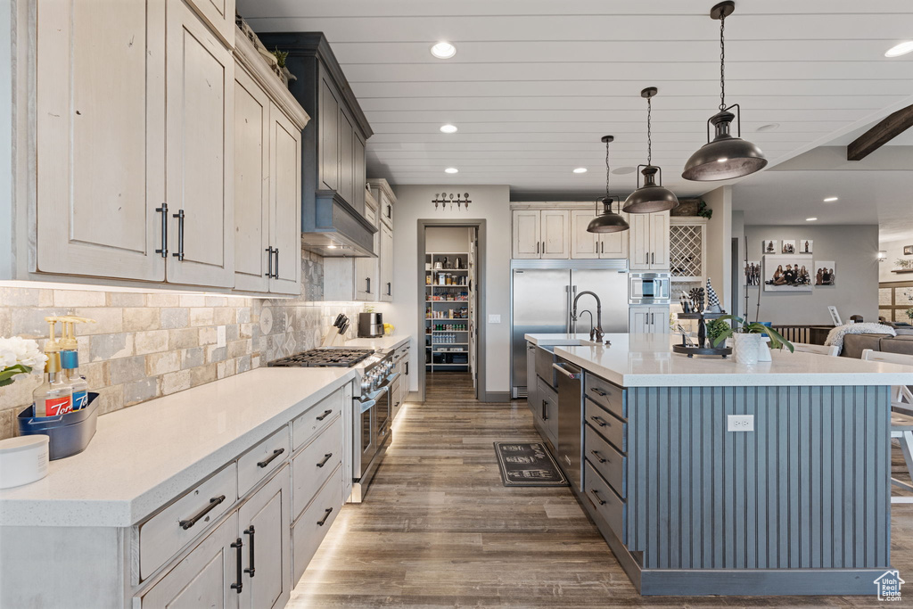 Kitchen with premium appliances, recessed lighting, wood finished floors, light countertops, and decorative light fixtures