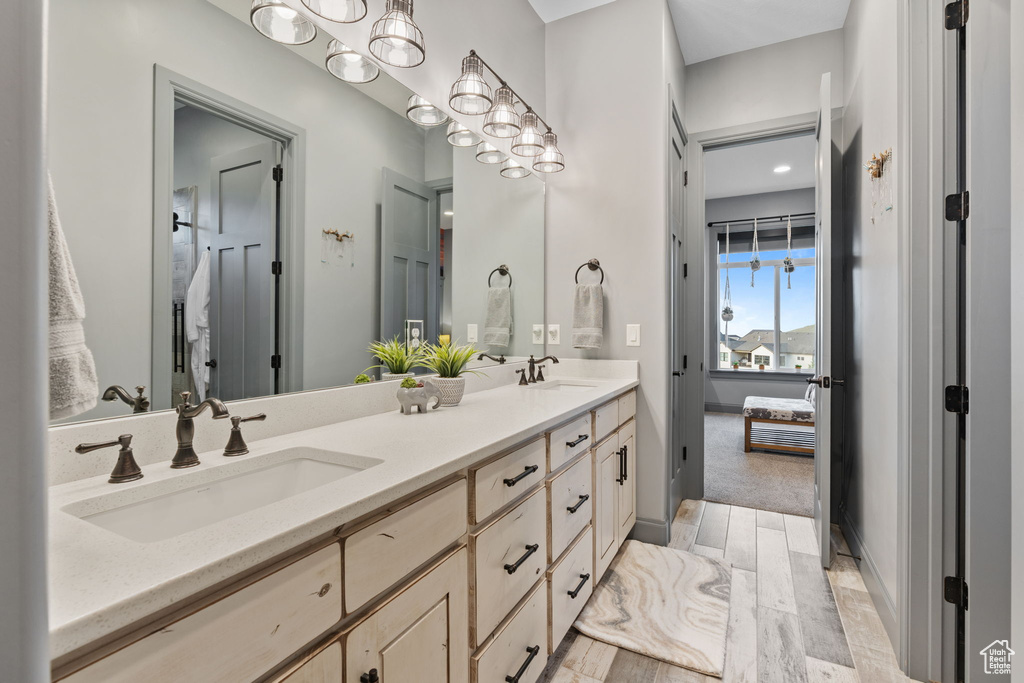 Ensuite bathroom with double vanity, a chandelier, and wood finished floors
