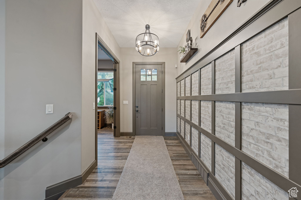 Foyer with wood finished floors, a chandelier, and baseboards