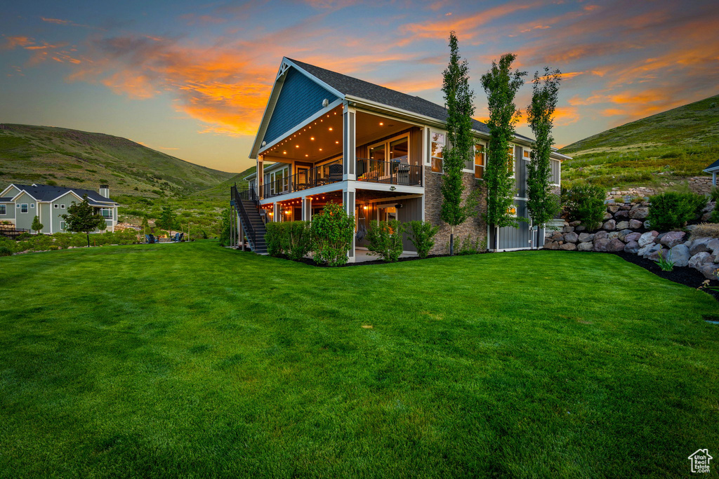 Back of property with stairway, a yard, and a deck with mountain view