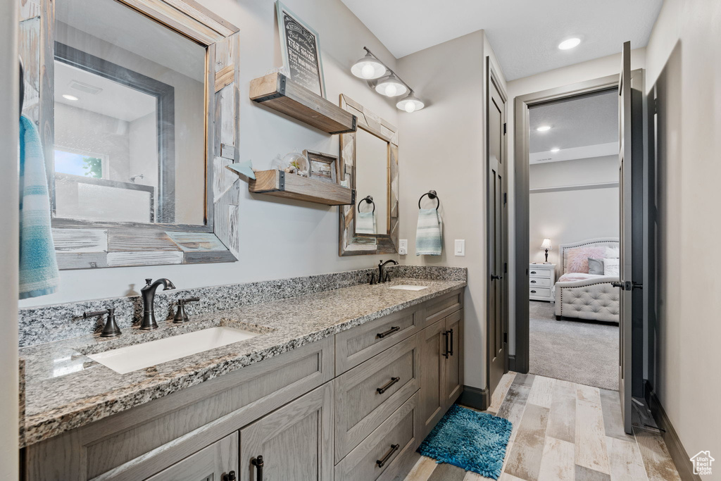 Ensuite bathroom featuring double vanity, wood finished floors, and recessed lighting