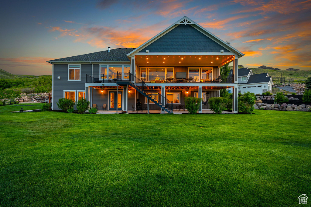 Back of house with a patio area, a deck with mountain view, stairs, and a yard