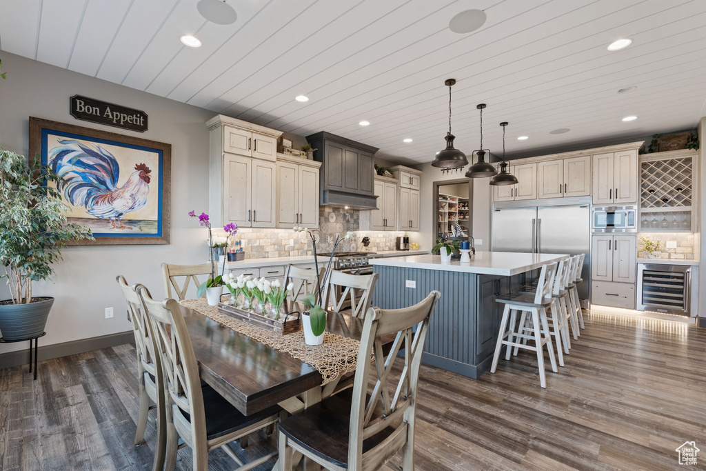 Dining space featuring wine cooler, recessed lighting, dark wood-style flooring, baseboards, and a bar