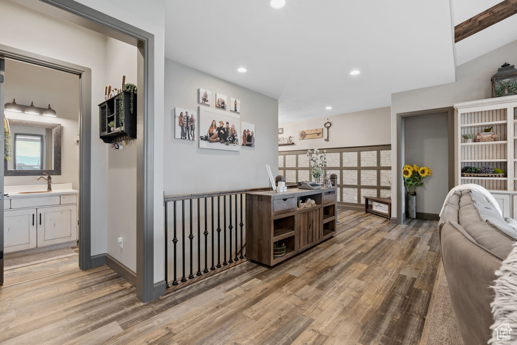 Hallway with light wood finished floors, recessed lighting, baseboards, and a sink