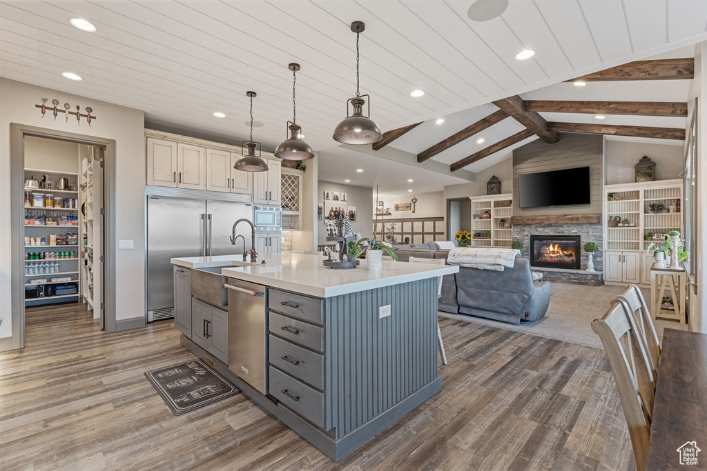 Kitchen featuring built in appliances, wood finished floors, gray cabinets, recessed lighting, and light countertops