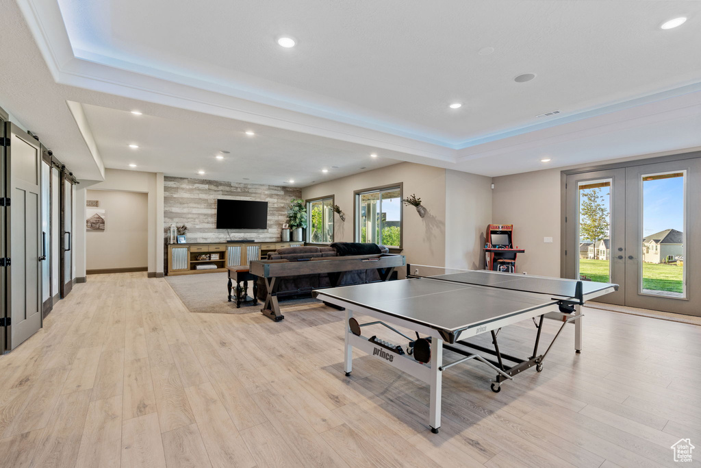 Recreation room featuring french doors, healthy amount of natural light, recessed lighting, light wood-style floors, and a tray ceiling