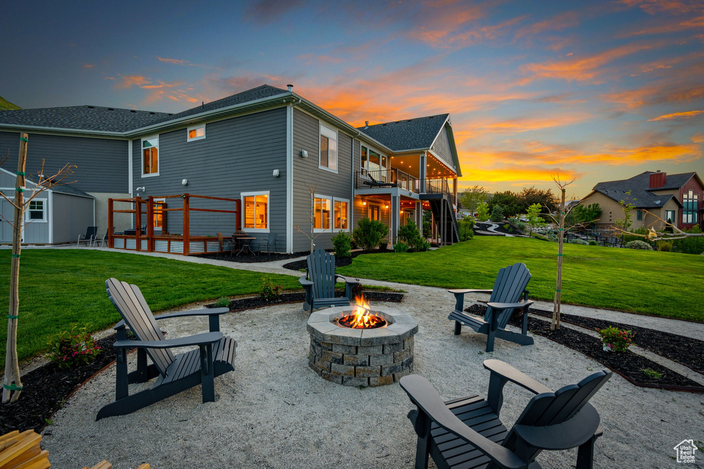 Rear view of house with a fire pit, a lawn, a patio, and a wooden deck