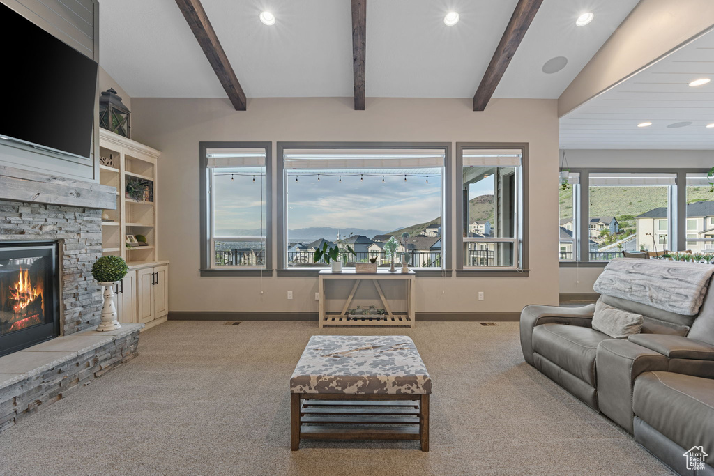Living room featuring carpet flooring, a stone fireplace, recessed lighting, baseboards, and beamed ceiling