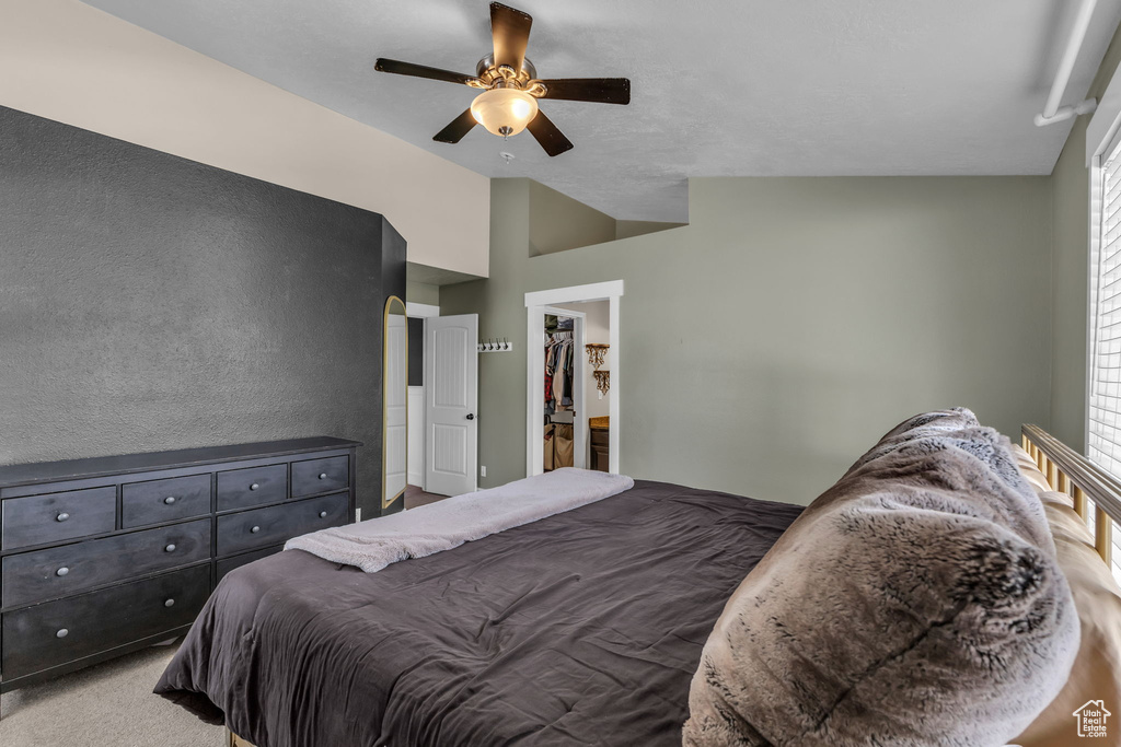 Carpeted bedroom featuring vaulted ceiling and ceiling fan