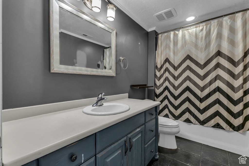Bathroom with vanity, toilet, shower / bath combo with shower curtain, and a textured ceiling