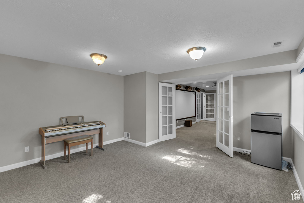 Finished below grade area with freestanding refrigerator, french doors, carpet floors, and baseboards