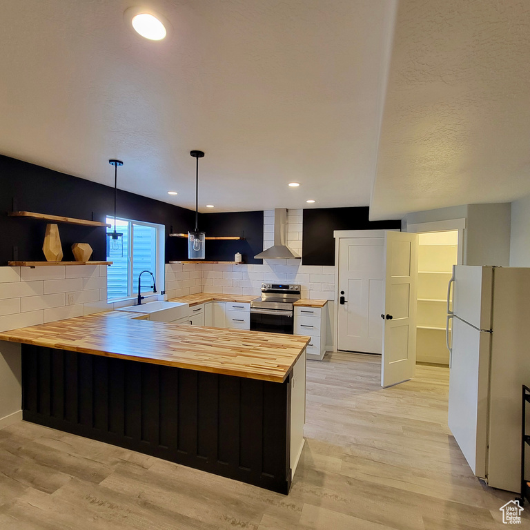 Kitchen with butcher block countertops, open shelves, a sink, freestanding refrigerator, and electric range