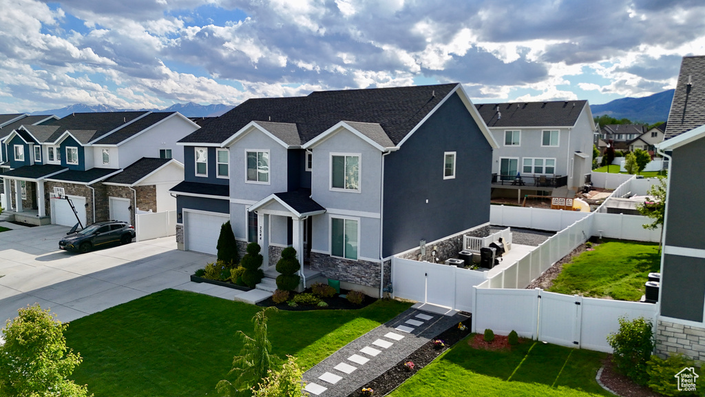 View of front of property with a residential view, a garage, concrete driveway, stucco siding, and stone siding
