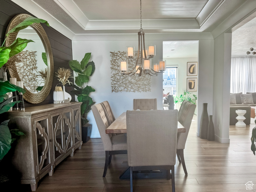 Dining room with a raised ceiling, a chandelier, hardwood / wood-style floors, and ornamental molding