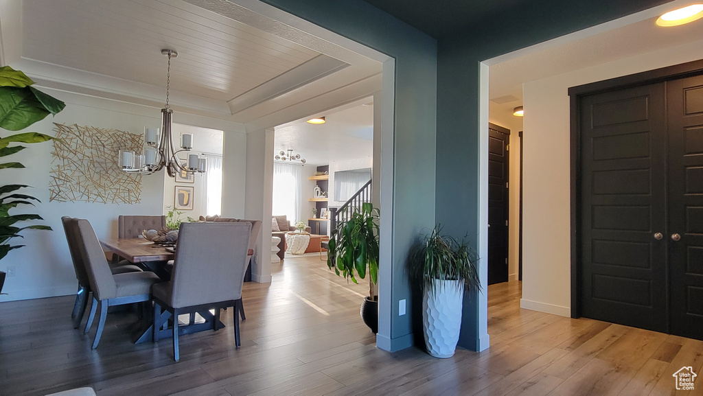 Dining room featuring a chandelier, a raised ceiling, and wood finished floors