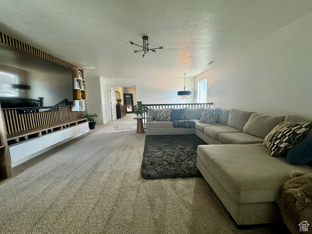 Living room with a chandelier, carpet flooring, and a textured ceiling
