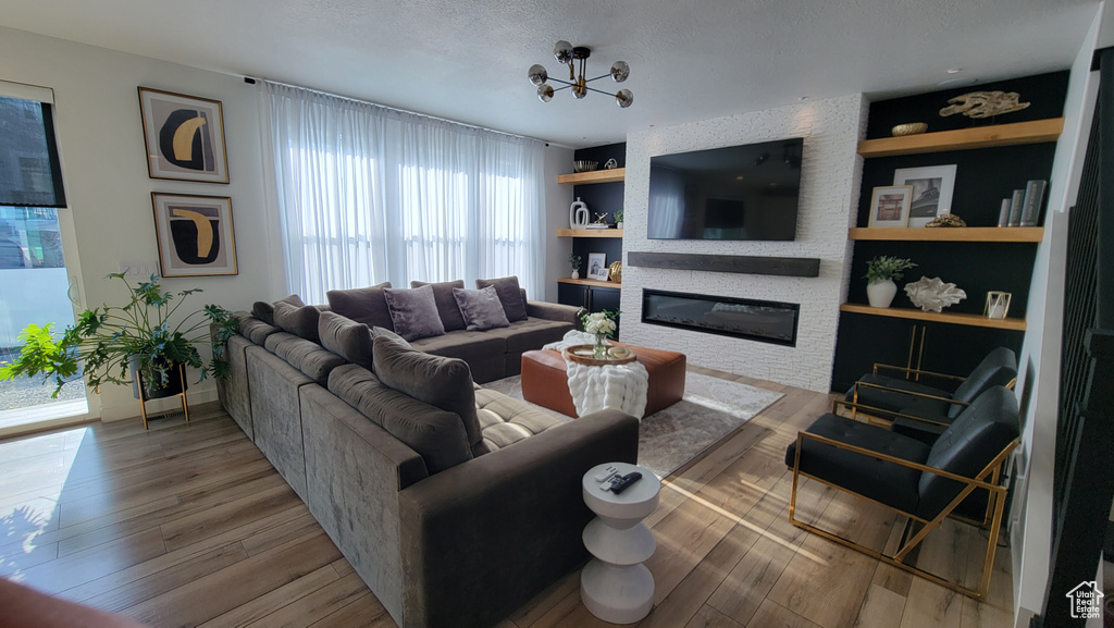 Living area with a large fireplace, built in shelves, wood finished floors, a textured ceiling, and baseboards