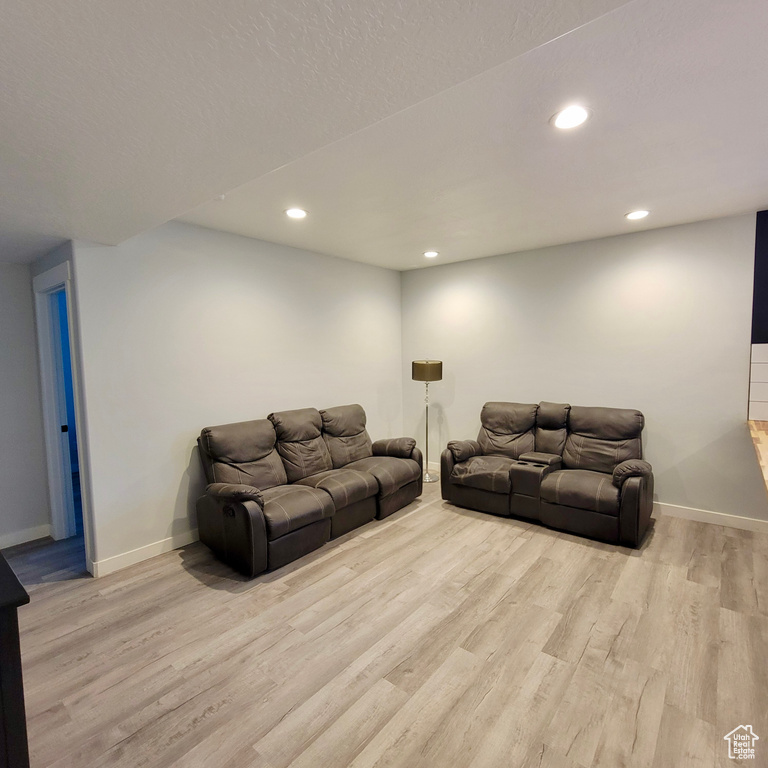 Living room with light wood-style floors, baseboards, and recessed lighting