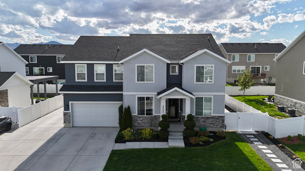View of front of home with stucco siding, stone siding, an attached garage, and concrete driveway
