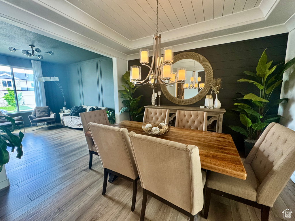 Dining area featuring a chandelier, a tray ceiling, wood finished floors, wooden ceiling, and ornamental molding