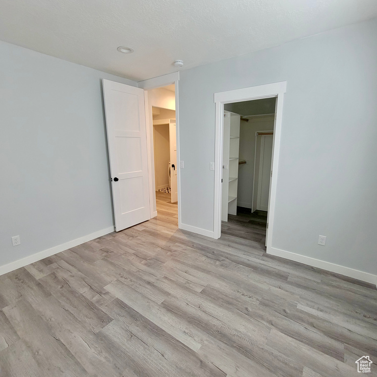 Unfurnished bedroom with light wood finished floors, baseboards, and a spacious closet