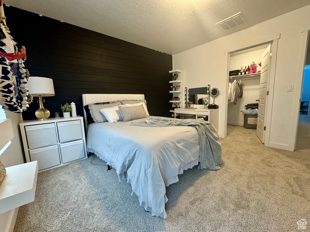 Carpeted bedroom with a spacious closet, a closet, and a textured ceiling
