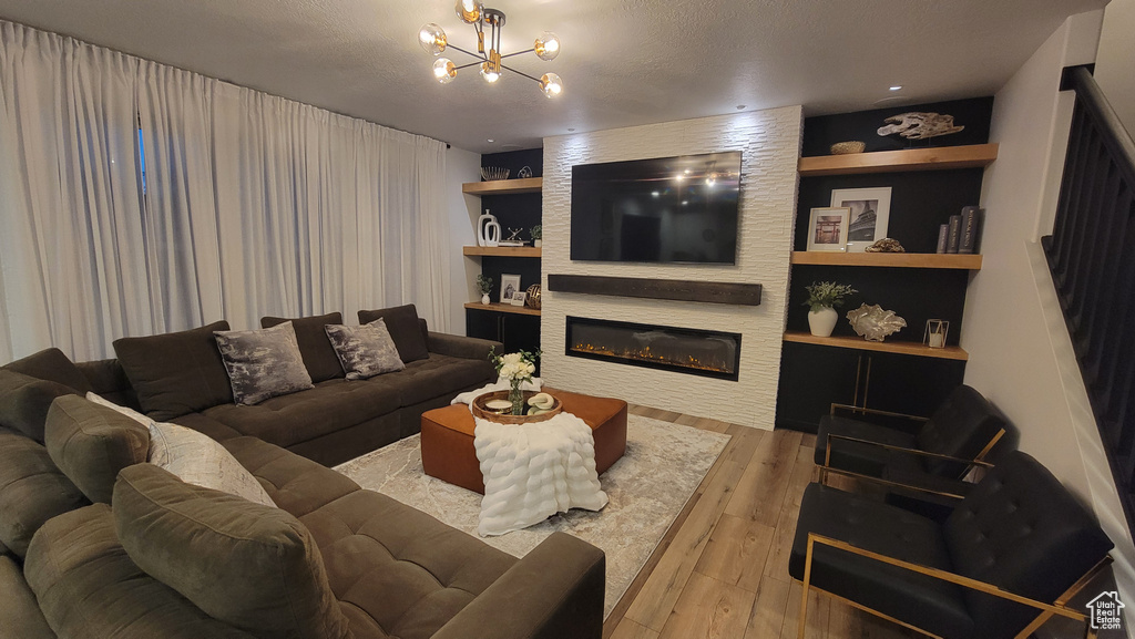 Living room featuring hardwood / wood-style flooring, a chandelier, a glass covered fireplace, and built in features