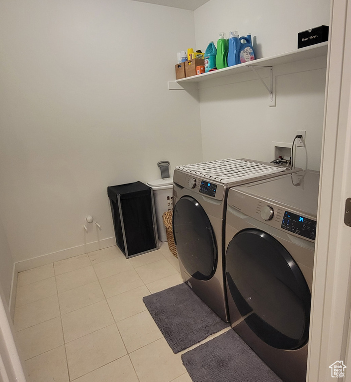 Washroom with light tile patterned floors, washer and dryer, and baseboards