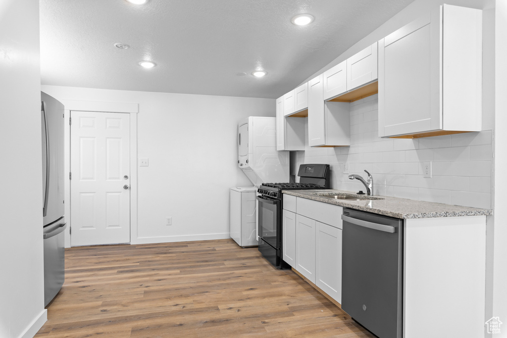 Kitchen featuring stainless steel appliances, a sink, backsplash, light stone countertops, and baseboards