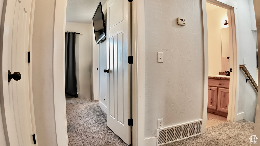 Hall featuring light carpet and a textured wall