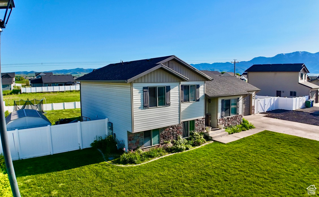 View of front of property featuring a mountain view, stone siding, concrete driveway, and board and batten siding
